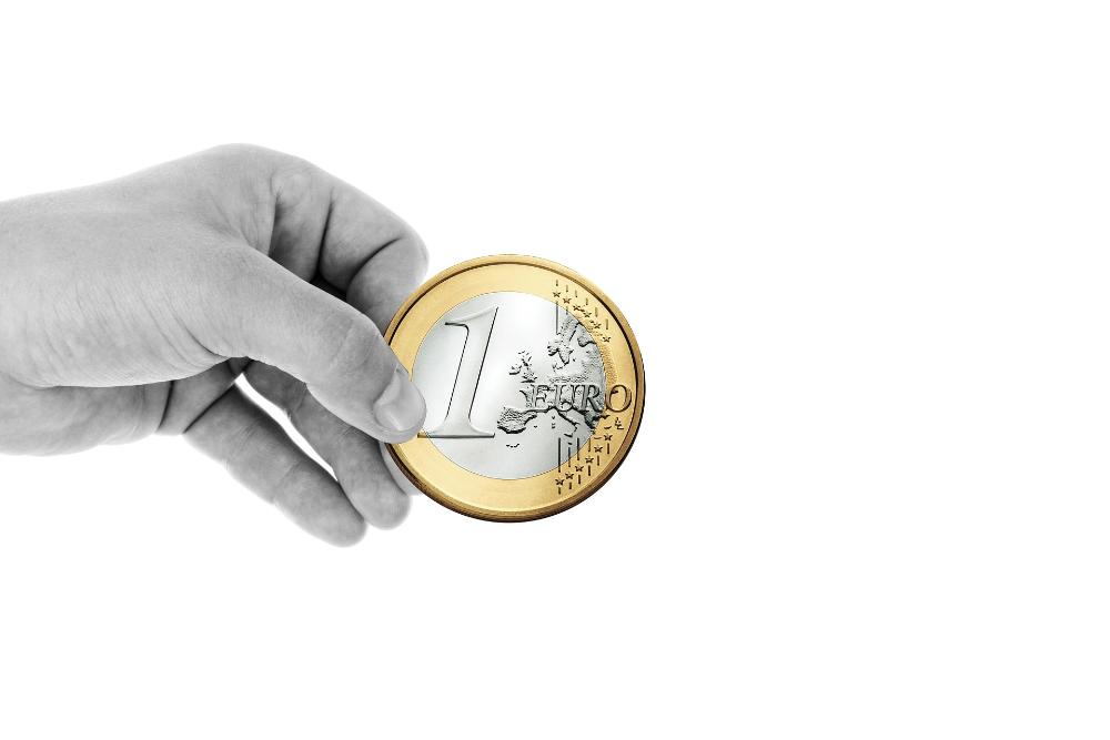 käsi, joka pitelee euron kolikkoa