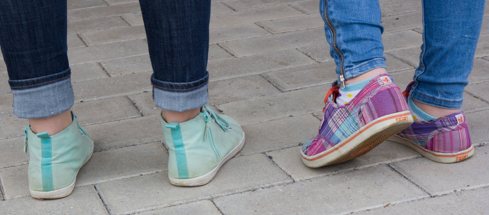 kaksi nuorta seisoskelee kuvassa näkyy heidän värikkättä kenkänsä